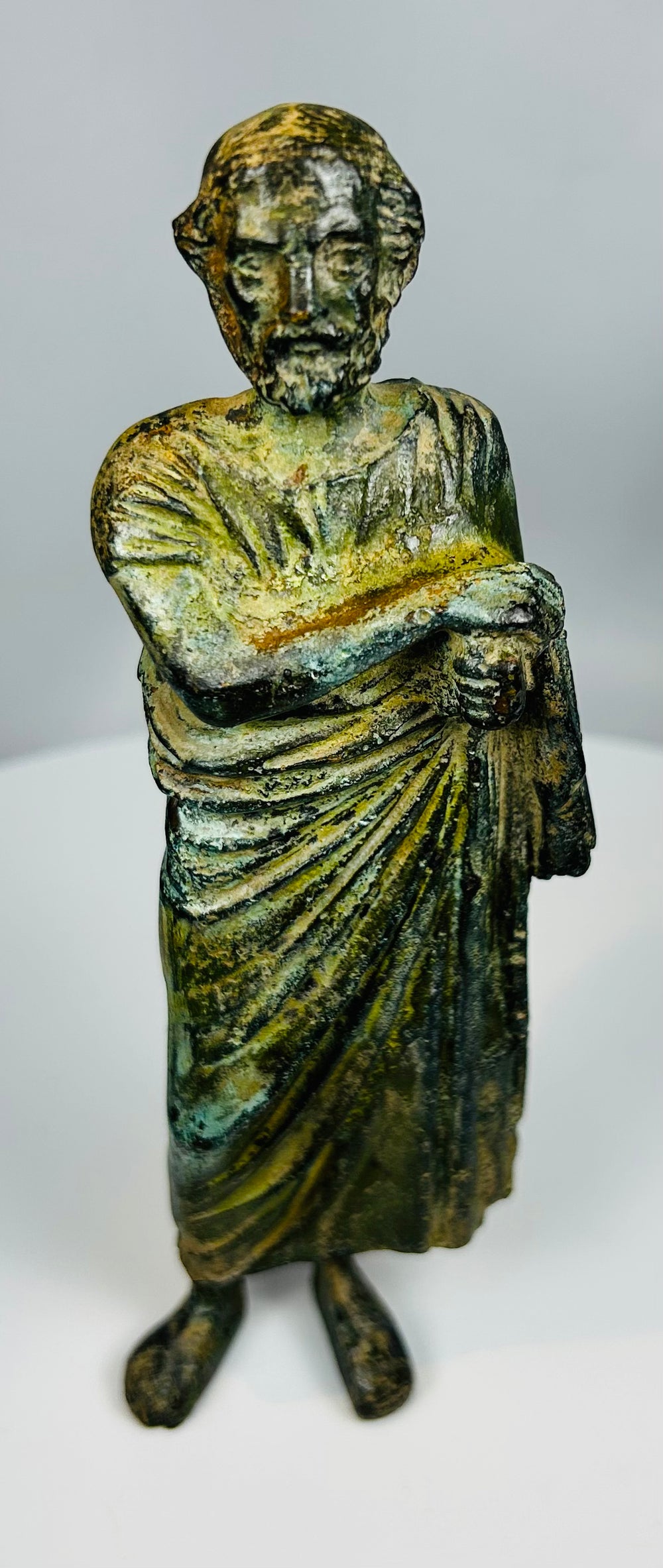 Antique bronze male statue with classical toga and rich green surface patina