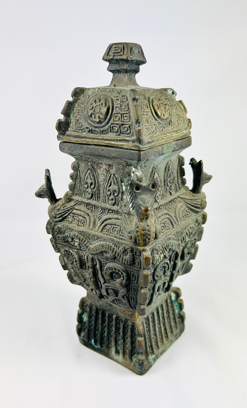 Chinese archaistic revival bronze fangyi with high relief taotie decoration and animal-head terminals, late 19th–early 20th century.
