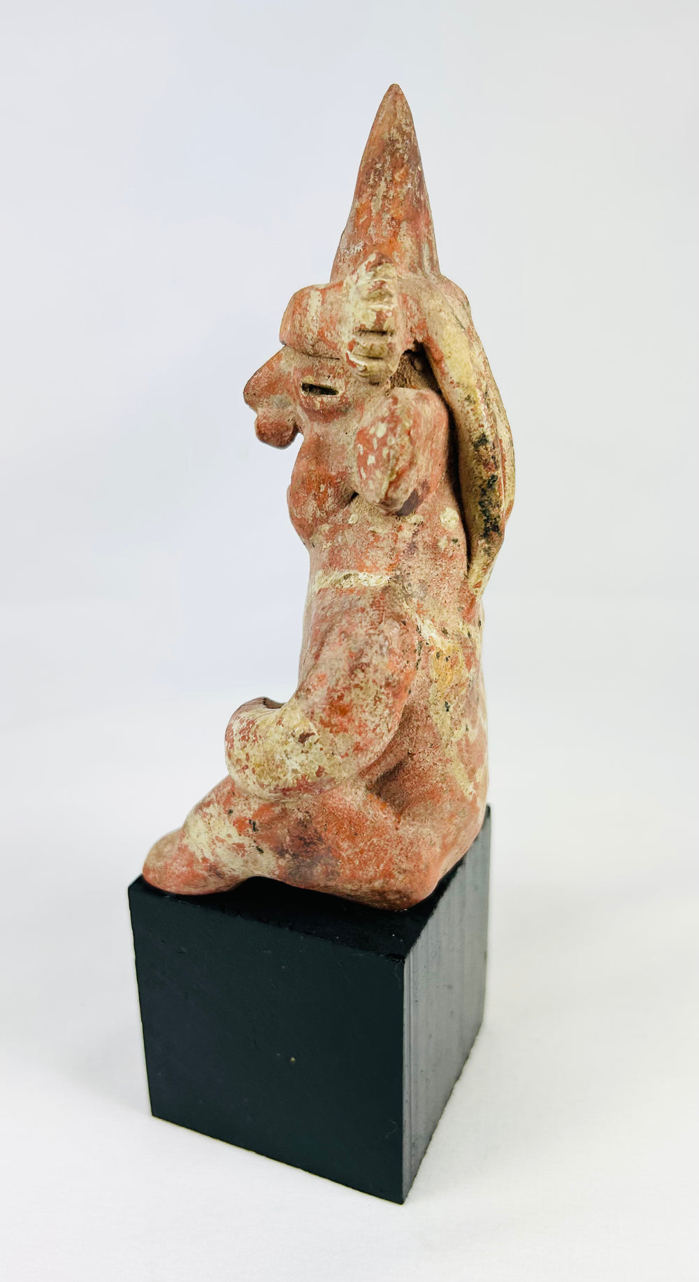Hollow-molded Nayarit ceramic seated figure with earspools and red slip remnants