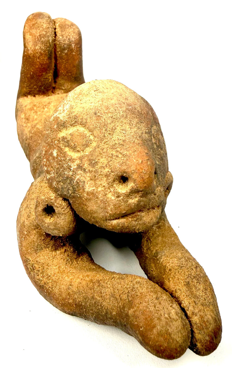 Ancient Pre-Columbian anthropomorphic figure featuring an oversized rounded head, stylized facial characteristics, and pierced ear ornaments.