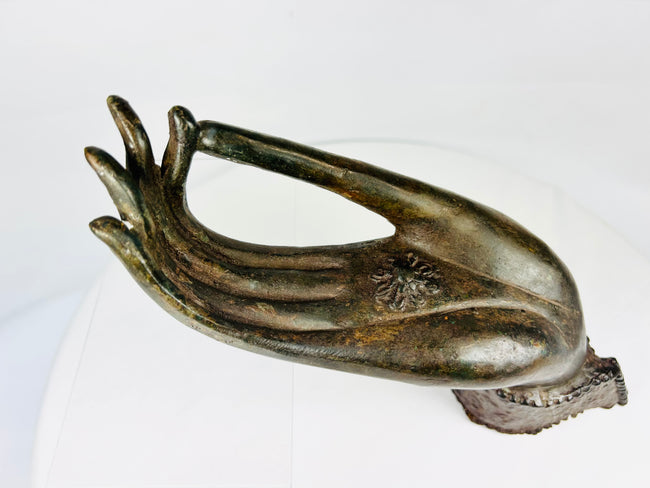 Northern Thai Buddhist bronze hand with symbolic chakra motif, antique fragment on display stand.