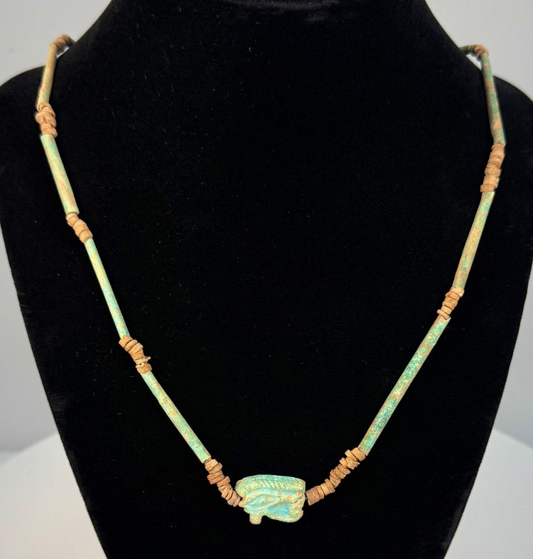 Egyptian Wedjat amulet necklace featuring a turquoise-green Eye of Horus pendant with raised protective symbolism and aged faience glaze.