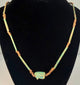 Ancient Egyptian faience amulet necklace with individually formed beads, aged surfaces, and traditional Wedjat protective imagery.