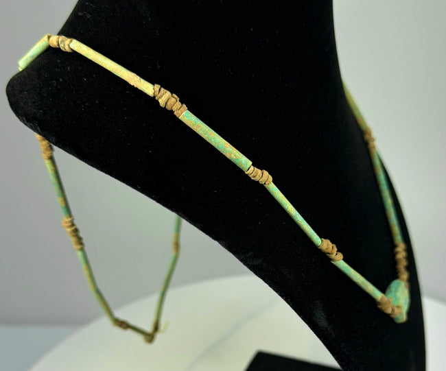 Egyptian Eye of Horus pendant displaying weathered turquoise glaze, sandy beige deposits, and intricately modelled symbolic detailing.