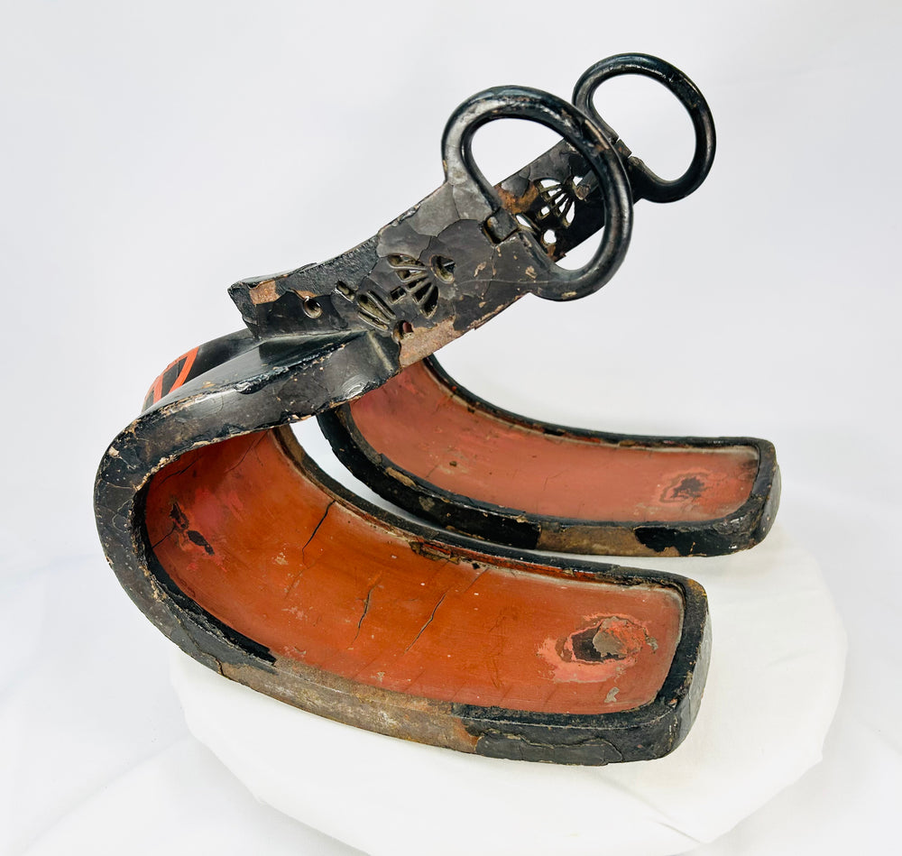 Pair of antique Japanese lacquered samurai stirrups from the Edo–Meiji period, showing red lacquered interiors and black exteriors with metal fittings, displayed on a white background.