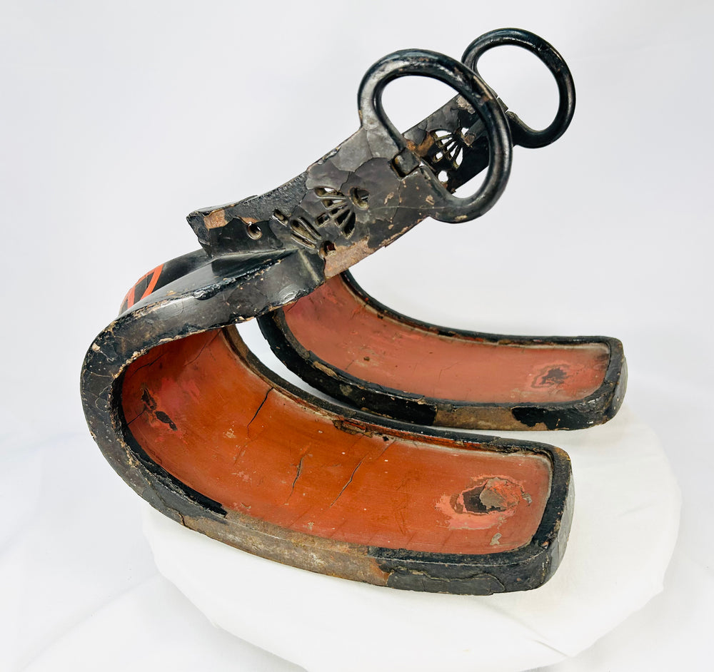 Pair of antique Japanese lacquered samurai stirrups from the Edo–Meiji period, showing red lacquered interiors and black exteriors with metal fittings, displayed on a white background.