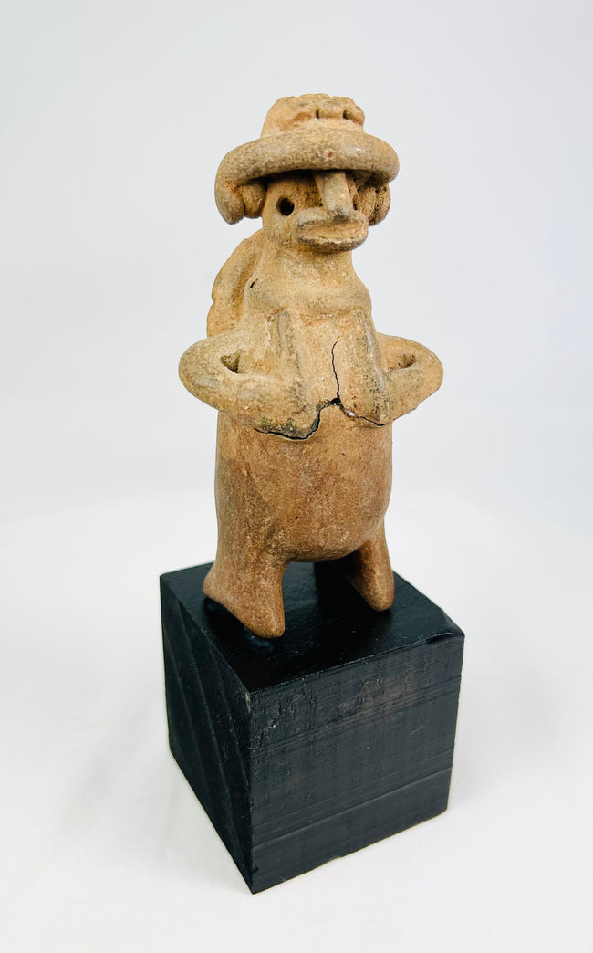 Terracotta effigy with turban-style headdress, large earspools, hands-to-chest pose, circular back disk