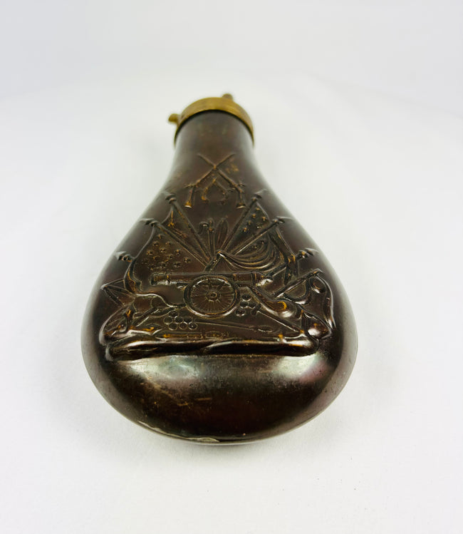 19th century American powder horn style flask in embossed copper with military stand of arms decoration, chocolate brown patina, collectible firearms accessory.