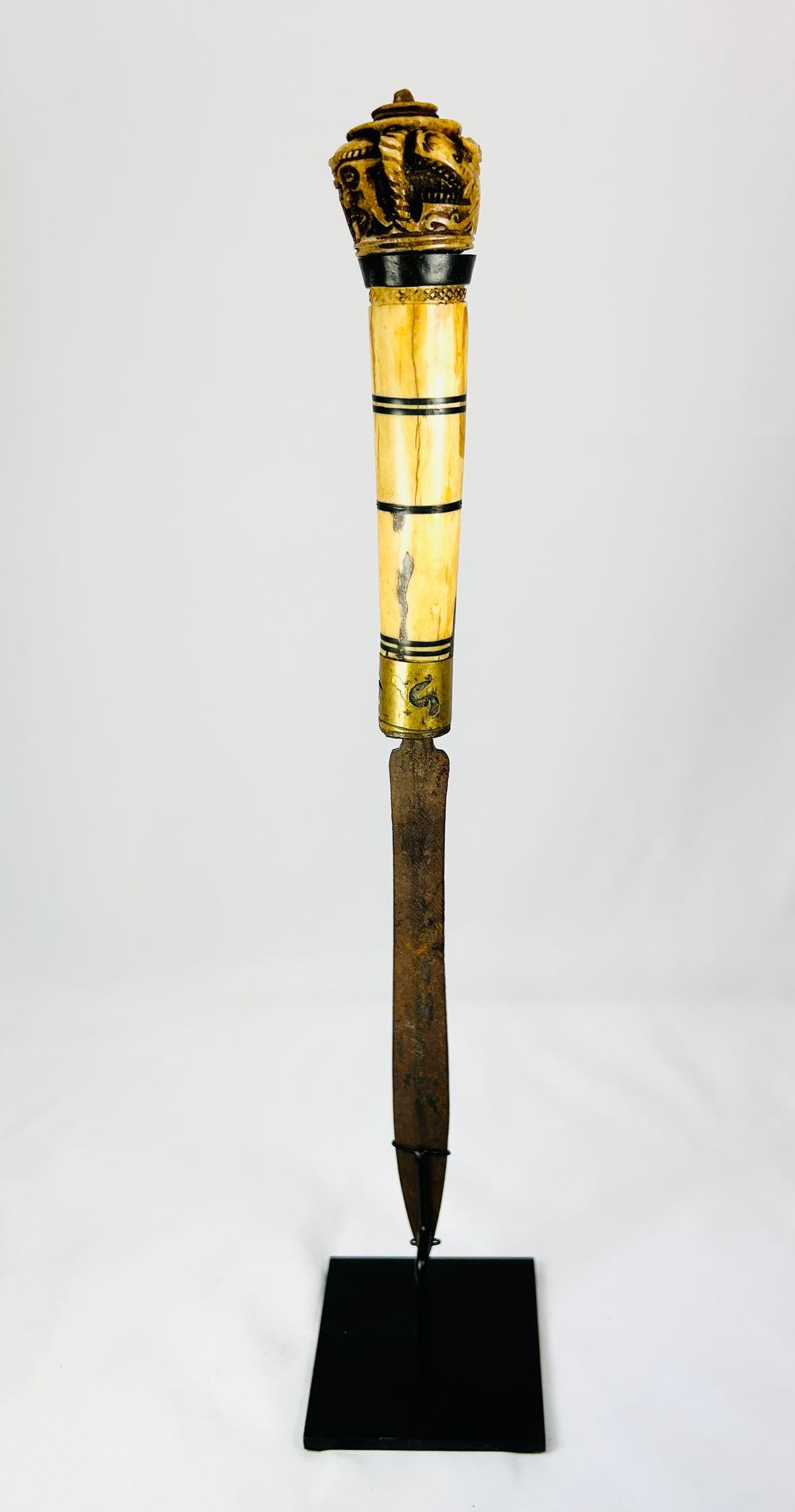 Antique Indonesian knife handle with detailed Dayak bone carvings, photographed up close.