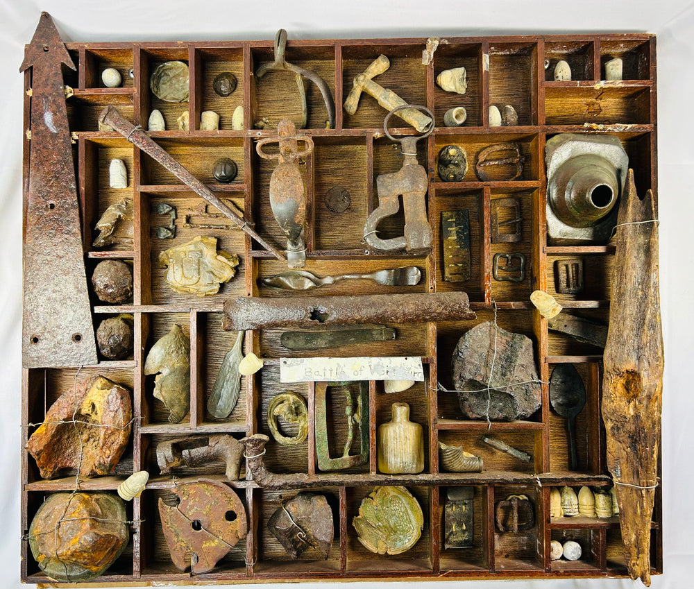 Civil War relic shadow-box display with dug artifacts including bullets, brass fittings, and tools arranged in a wooden compartment tray.