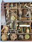 Excavated Civil War artifacts organized in a wooden display tray, featuring Minie balls, buckles, canteen spout, and iron camp tools.
