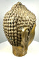 Mid-20th-century golden Buddha head statue with a contemplative smile, softly modelled lips, and intricate spiral hair detailing.