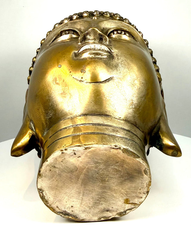 Mid-20th-century cast-metal Buddha head showing underside finishing marks, textured metal surfaces, cylindrical neck construction, and aged golden patination.