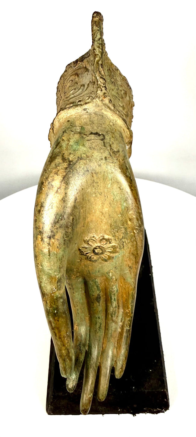 Antique bronze Buddha hand with a centrally positioned floral rosette, elongated fingers, and darkened patination emphasizing its sculptural details.