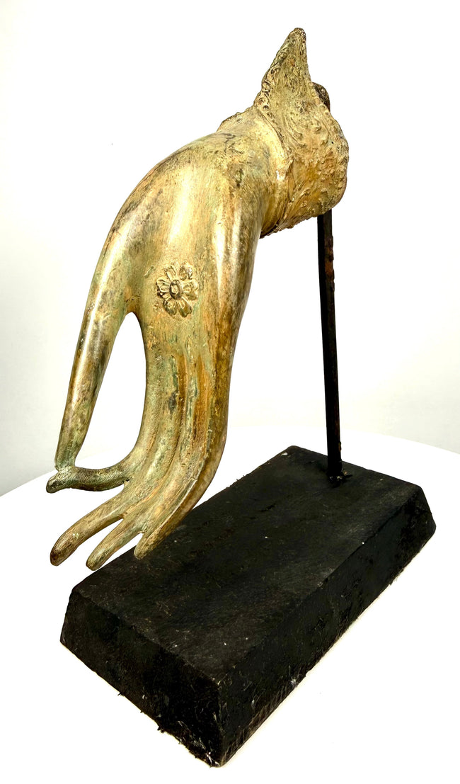 Thai Buddhist devotional sculpture displaying decorative wrist ornamentation, raised floral scrollwork, and contrasting golden and dark-brown bronze surfaces.