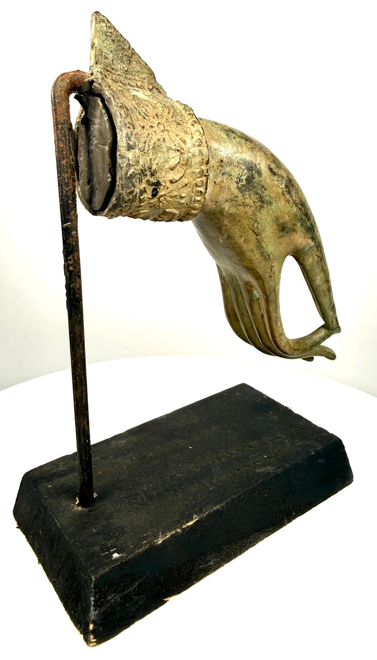 Thai Buddhist hand fragment mounted on a black rectangular display base with an upright metal support, highlighting its elegant form and sculptural detailing.