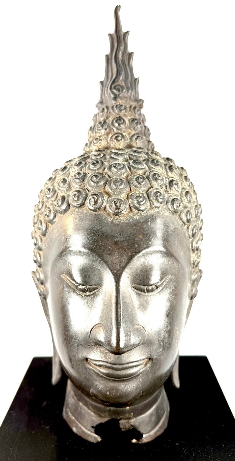 Thai Sukhothai-style Buddha sculpture with elongated downcast eyes expressing peaceful meditation and spiritual tranquillity.