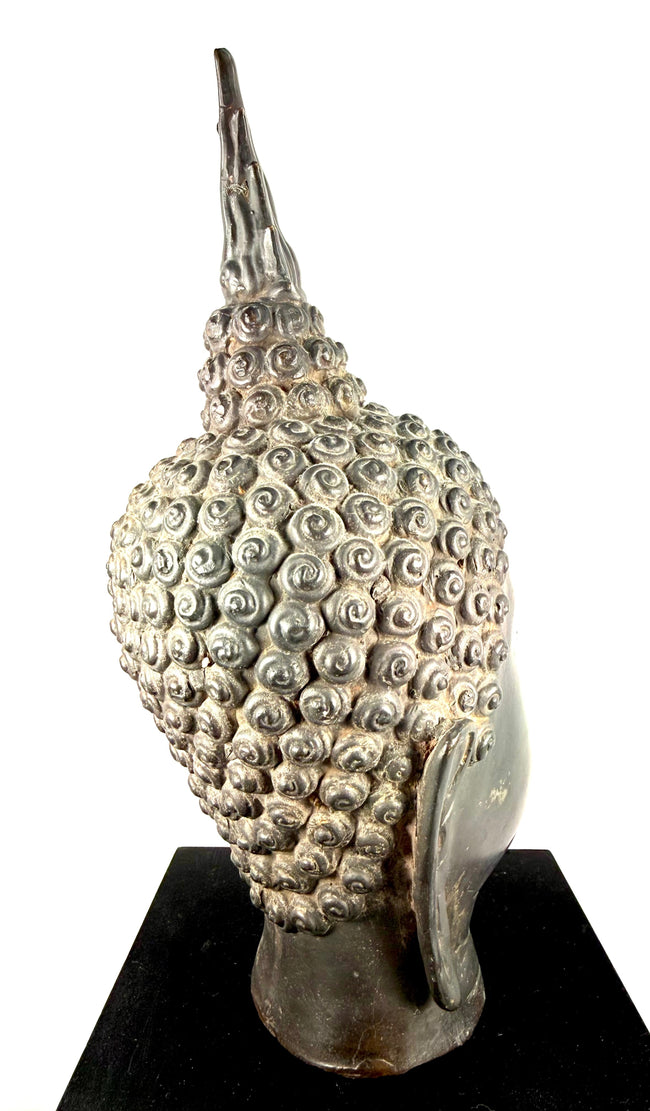 Thai Buddha head with elongated earlobes symbolizing the renunciation of worldly wealth in Buddhist tradition.