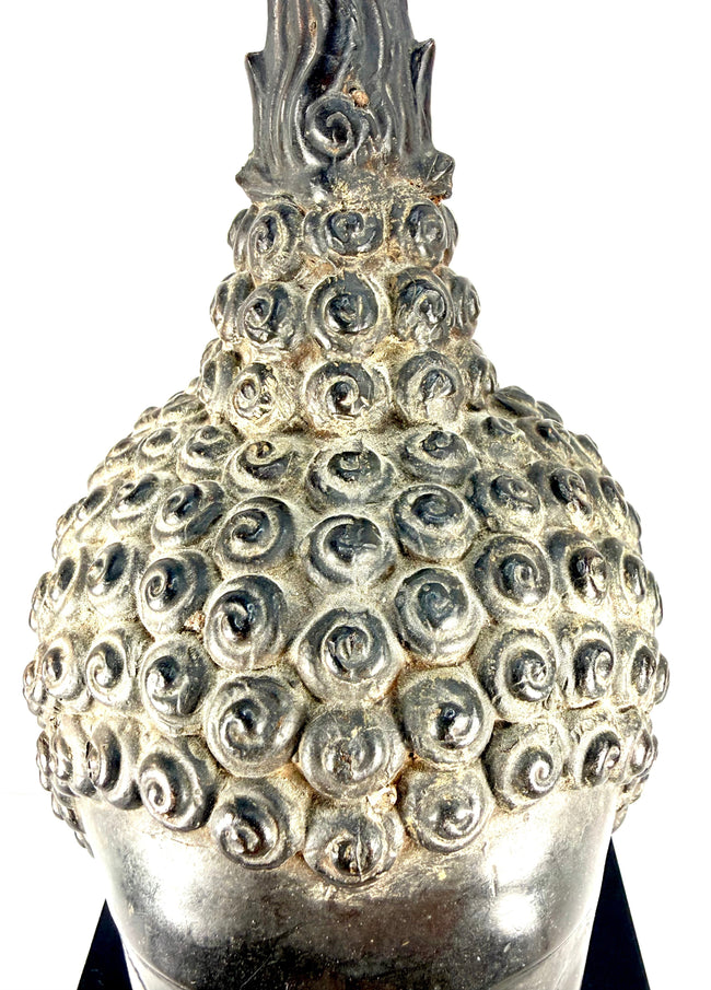 Cast copper-alloy Buddha head displaying dark grey-brown metallic patination and contrasting surface highlights.