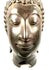 Antique Buddhist sculpture with polished metallic highlights across the forehead, cheeks, nose, and gently smiling lips.