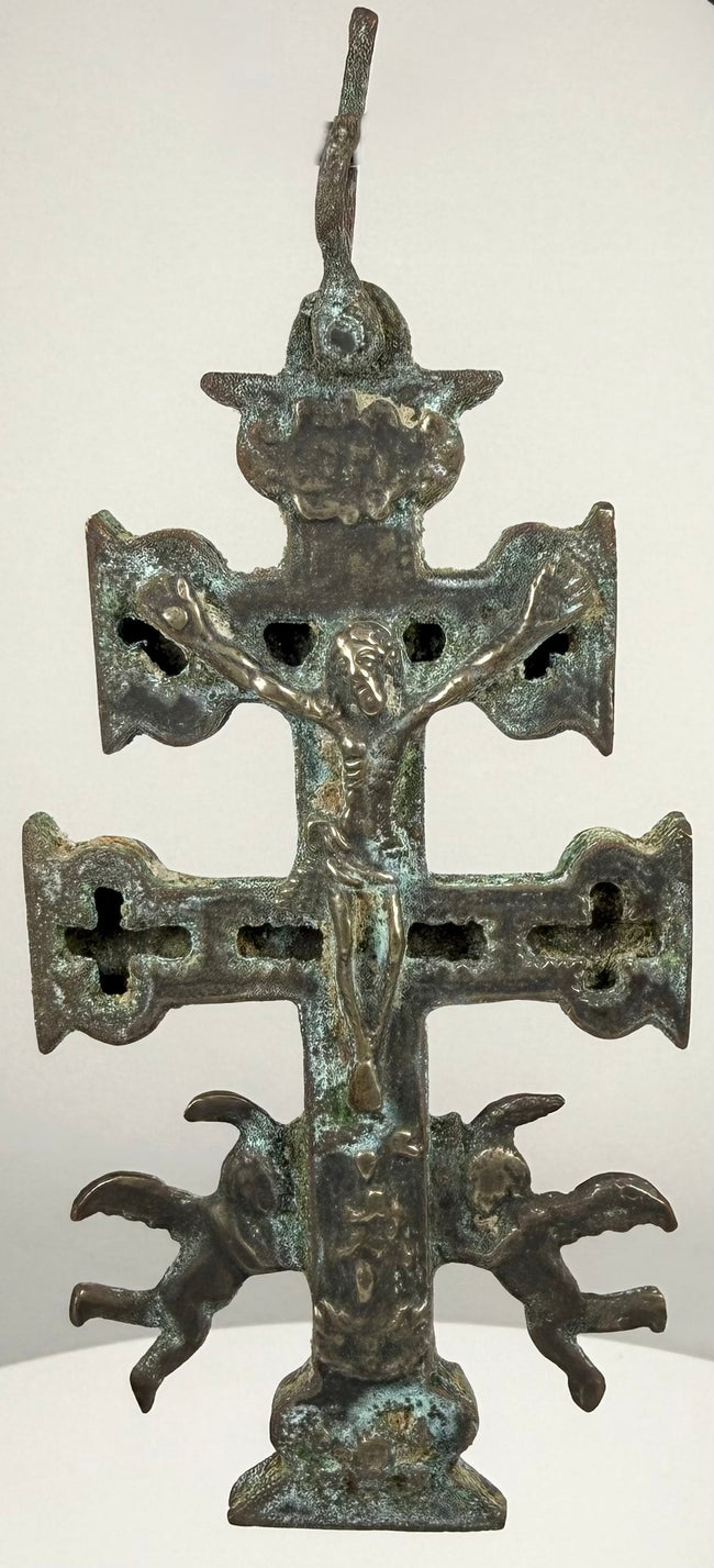 Historic Cross of Caravaca featuring two winged angels with outstretched wings, detailed sculptural forms, and turquoise copper oxidation.