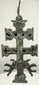 Historic Cross of Caravaca featuring two winged angels with outstretched wings, detailed sculptural forms, and turquoise copper oxidation.