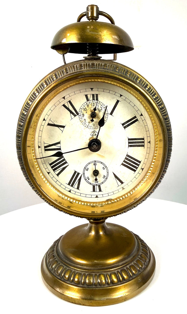 Historic German pedestal alarm clock with a prominent domed brass bell, exposed striking mechanism, and circular carrying ring.