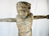 Religious wooden sculpture of Christ in cruciform pose with visible tool marks