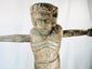 Religious wooden sculpture of Christ in cruciform pose with visible tool marks