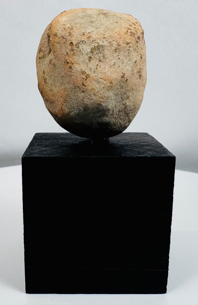 Stylized Pre-Columbian terracotta face fragment mounted for display with visible weathering and age.