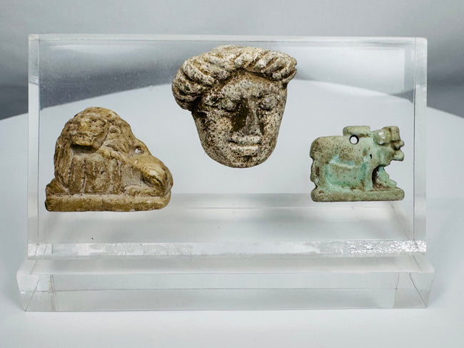 Ancient Mediterranean study collection featuring Egyptian devotional amulet and two carved stone figures.