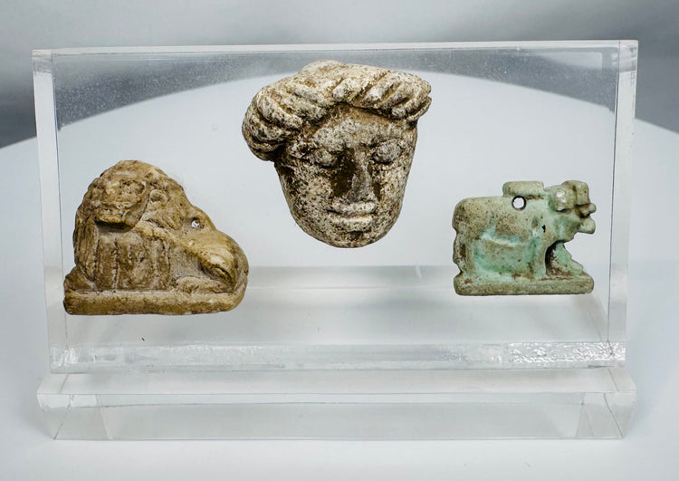 Ancient Egyptian and Greco-Roman antiquities mounted in a clear display case featuring religious and figural carvings.