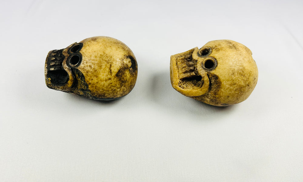 Side profile of Tibetan ritual skull beads carved from human bone, displaying aged patina and vertical suspension holes