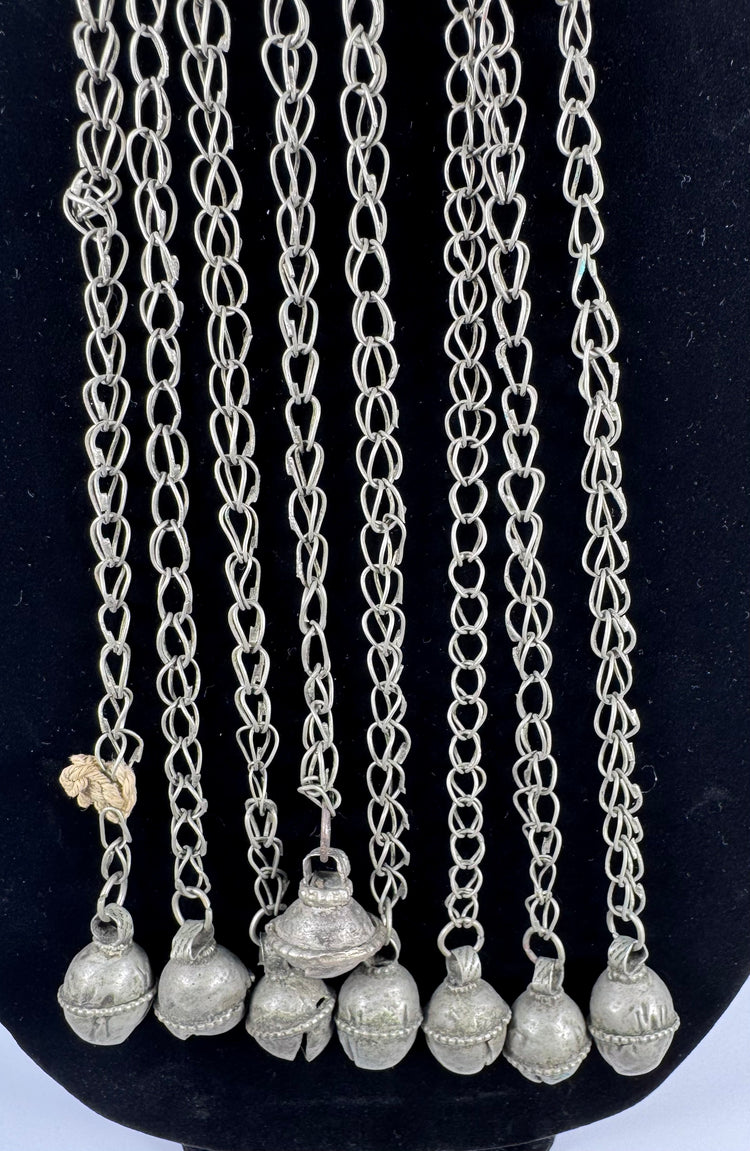Afghan tribal pendant displaying handcrafted silver-toned metalwork, red glass accents, and ceremonial chain tassels.