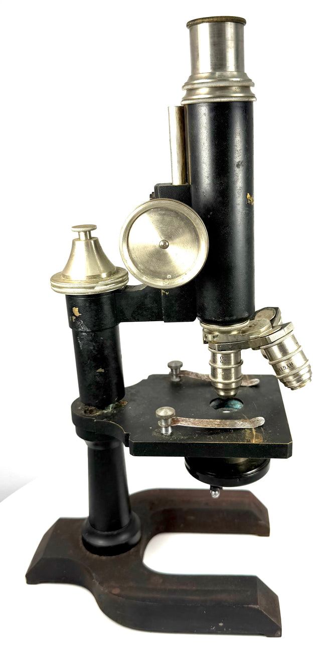 Side view of an early 1900s Spencer compound microscope displaying its specimen stage, focusing mechanism, optical objectives, and metal stand.
