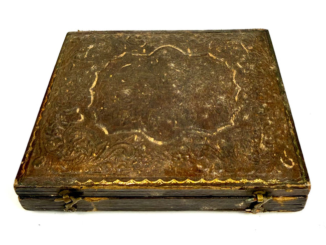 Closed Victorian photographic case from circa 1850–1865, featuring an embossed exterior with intricate floral and scrolling ornamentation.