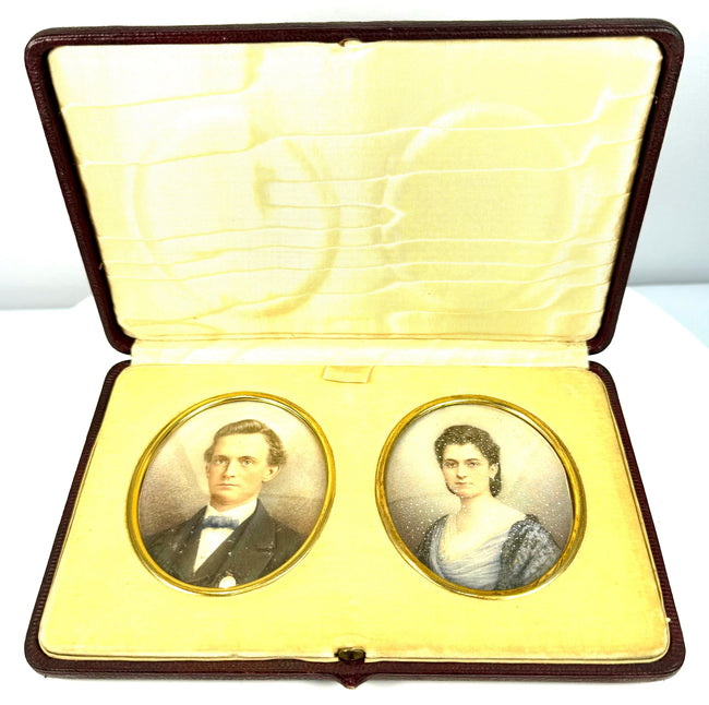 Front view of two antique colour portrait miniatures arranged side by side within an elegant burgundy leather-covered presentation case.