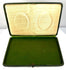 Angled view of an open Victorian–Edwardian presentation case showing paired oval portraits and decorative cream satin-like lining.