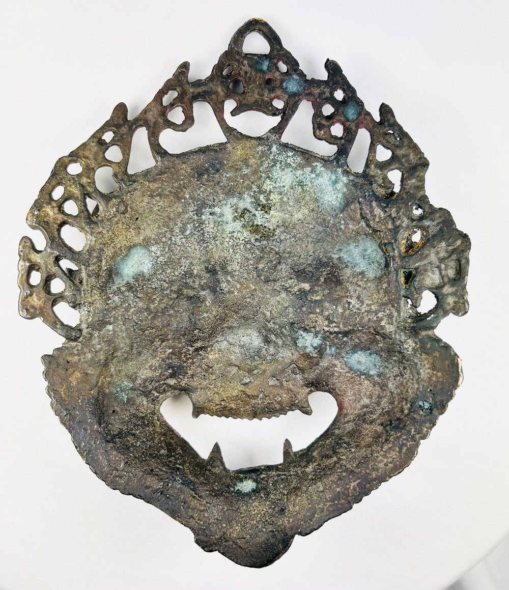 Antique Himalayan devotional mask with grimacing mouth, staring eyes, and ritual accretions