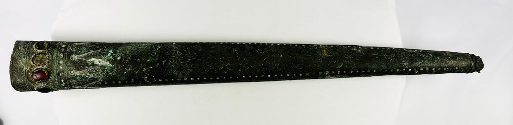 Full side view of engraved Etruscan bronze sword sheath showing dotted repoussé details and gemstone inlays – 9th–7th century BCE artifact with aged patina