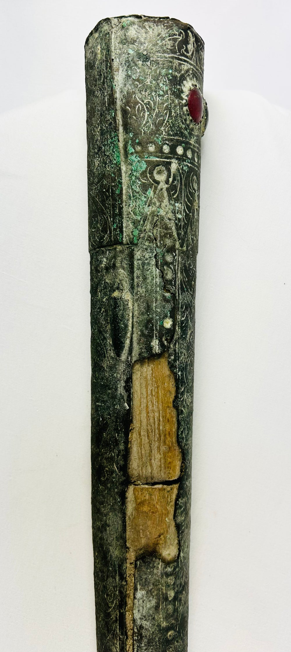 Vertical view of upper Etruscan bronze sword sheath with intricate carvings, gemstone inlay, and bronze patina – early Iron Age artifact