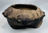 Close-up of the modeled zoomorphic heads decorating the rim of an authentic Pre-Columbian terracotta tripod vessel.