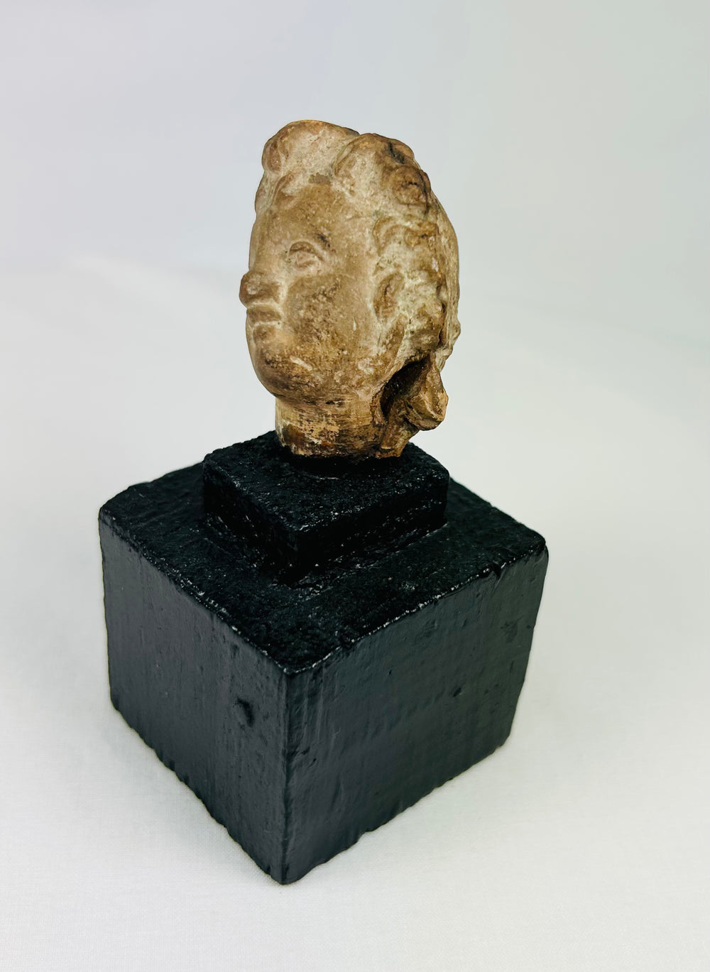 Ancient Greek or Roman-style head fragment, terracotta or stone, warm patina, mounted artifact