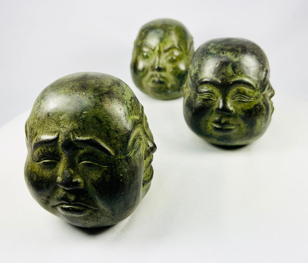 Cast metal Buddha head figures from Himalayan region displayed in brocade case