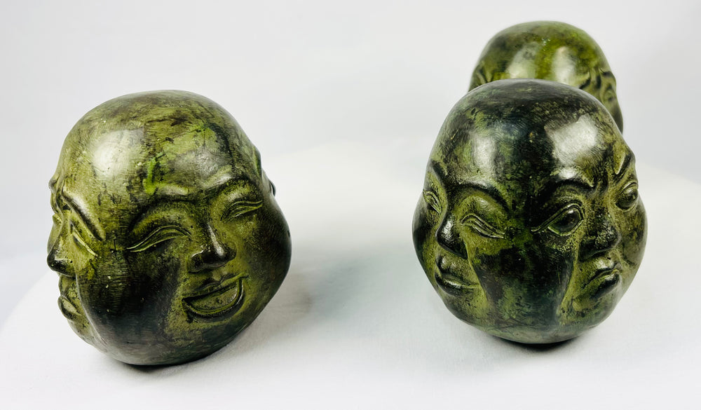 Traditional Buddhist metal head sculptures with mottled green patina surfaces