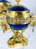 Close-up of a Louis XVI Revival vase displaying cobalt-blue porcelain, lion mask mounts, and ring handles.