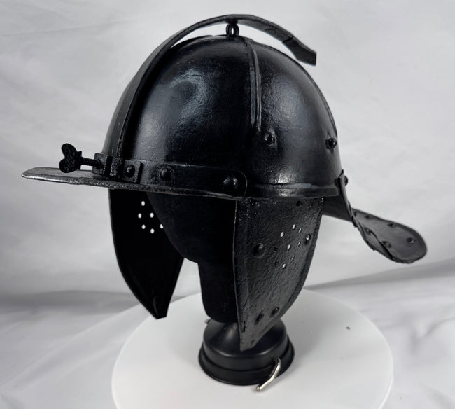 Historic Northern European cavalry helmet with pierced ear guards, adjustable nasal bar, and aged black finish.
