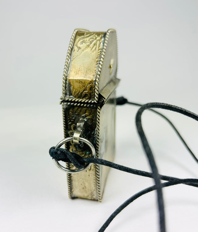 Silver repoussé Tibetan gau featuring floral and symbolic ornamentation

