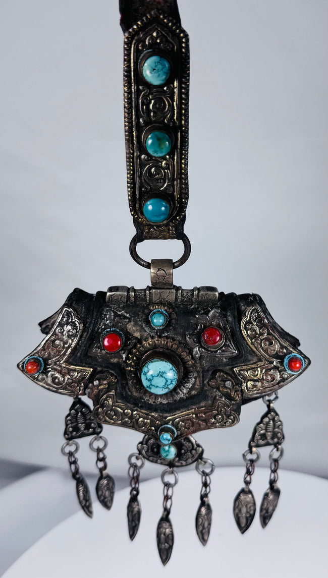 Late 19th century Tibetan ceremonial chest ornament with silvered metal, turquoise, coral, and hanging pendants.