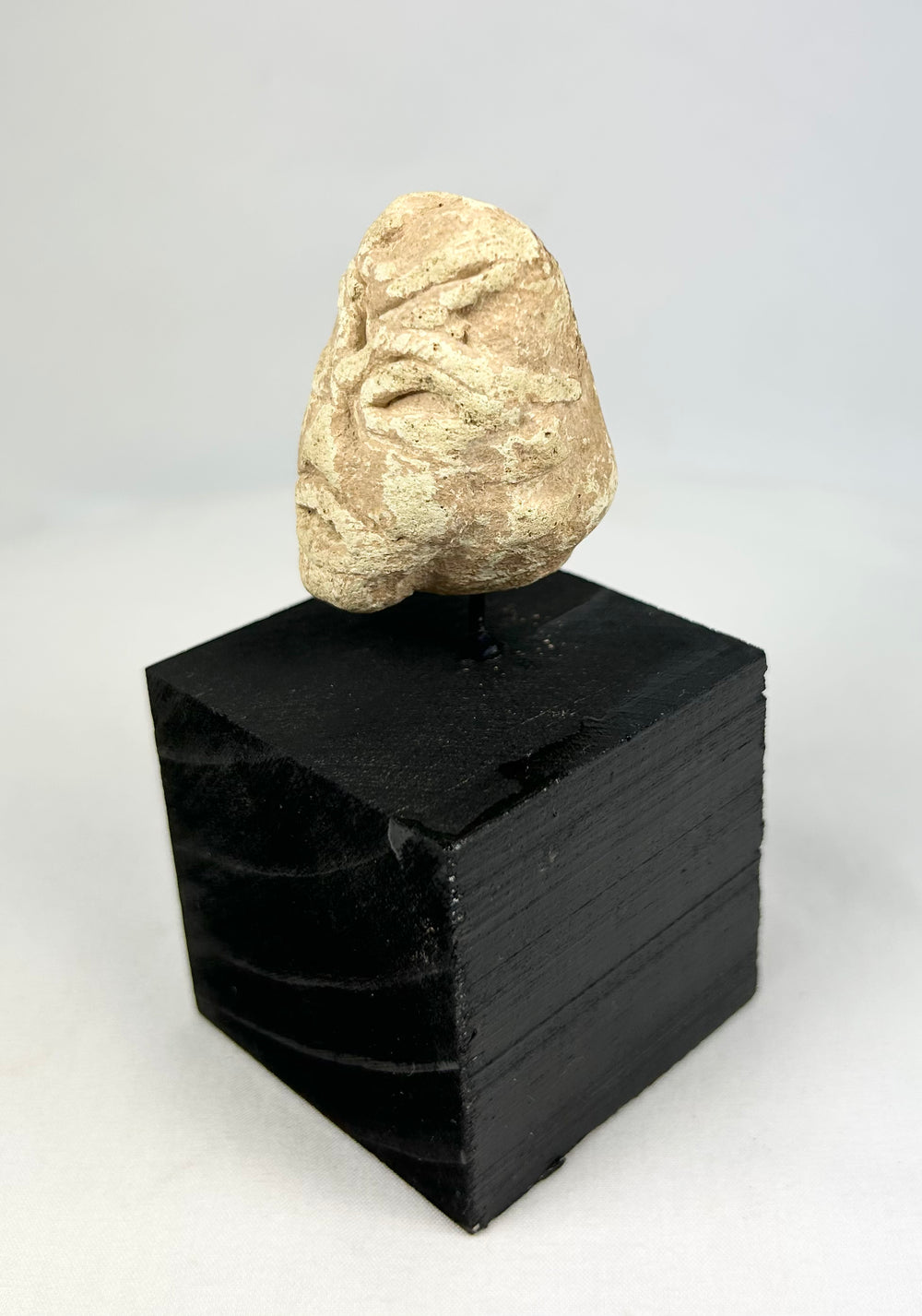 Mesopotamian stone votive head fragment, 2000–800 BCE, carved idol with almond-shaped eyes on display stand